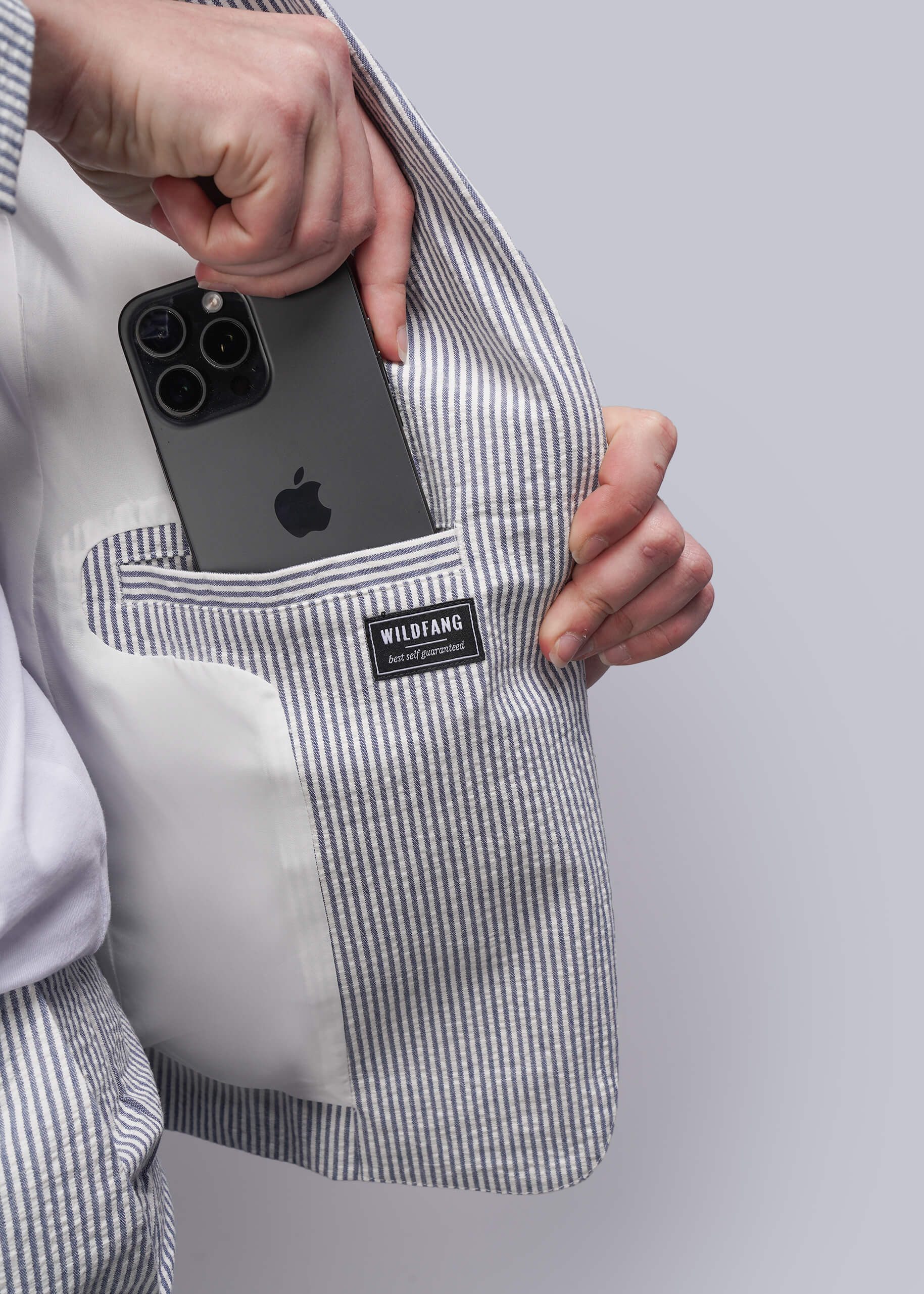 S=Person holding a phone in a striped blazer pocket with 'WILDANG' branding.