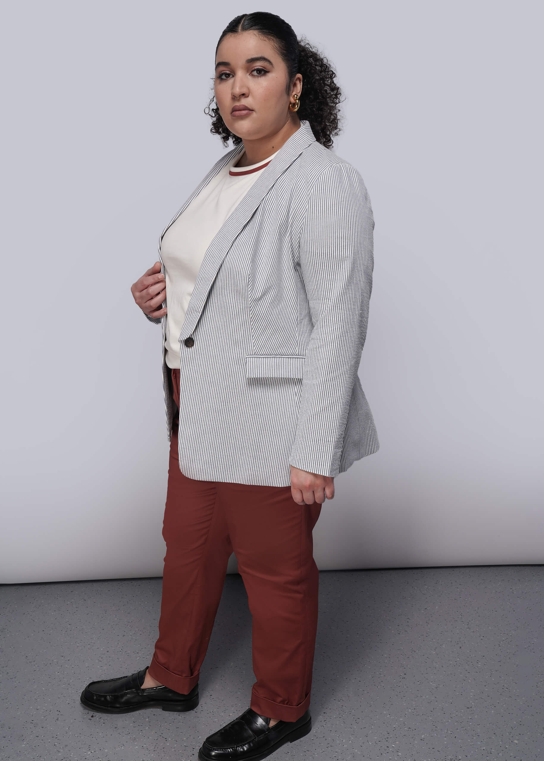 1X=Person wearing a light blue striped seersucker blazer, white shirt, red pants, and black shoes on a plain background