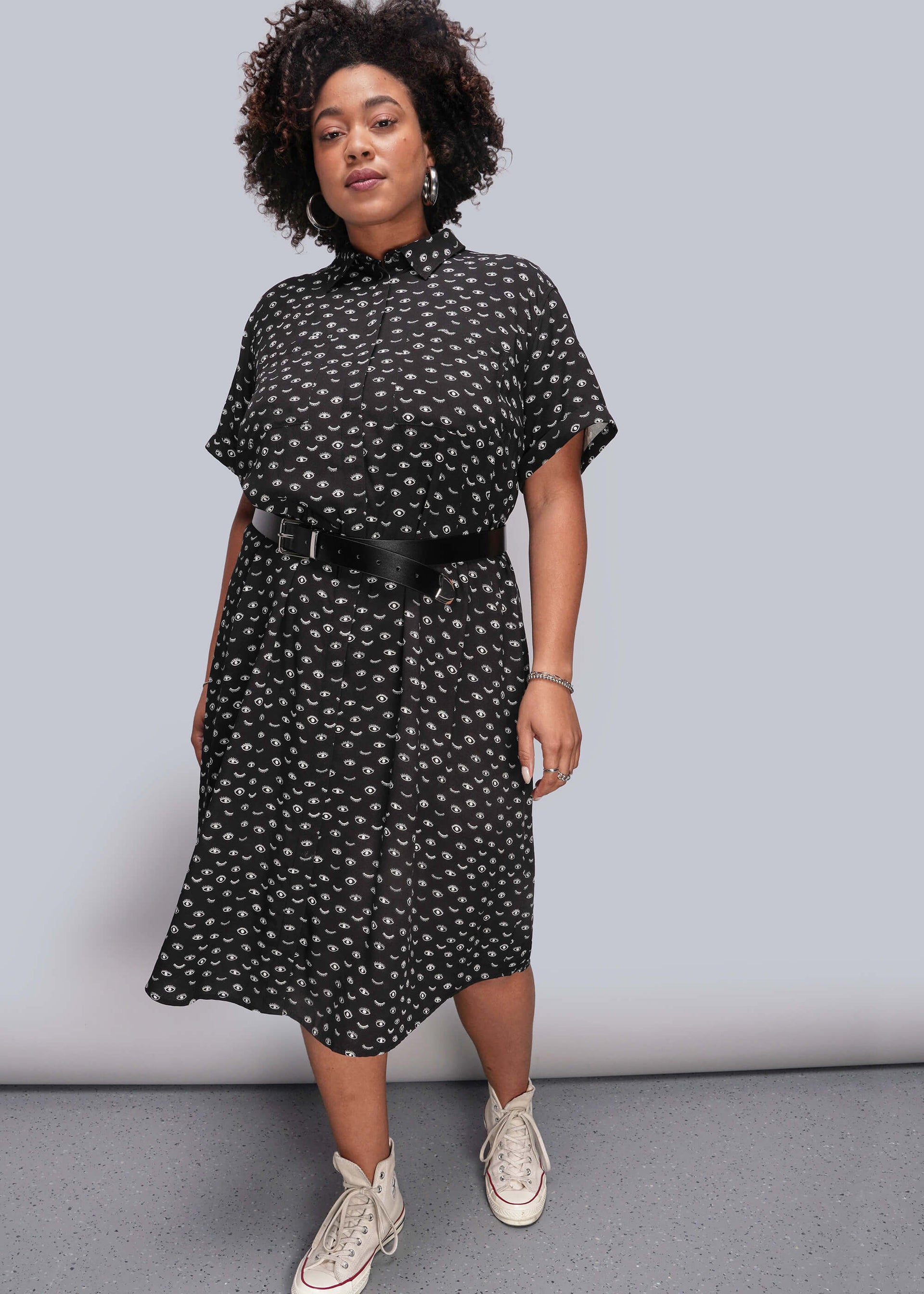 1X=Person wearing a black and white patterned dress with a belt against a gray background