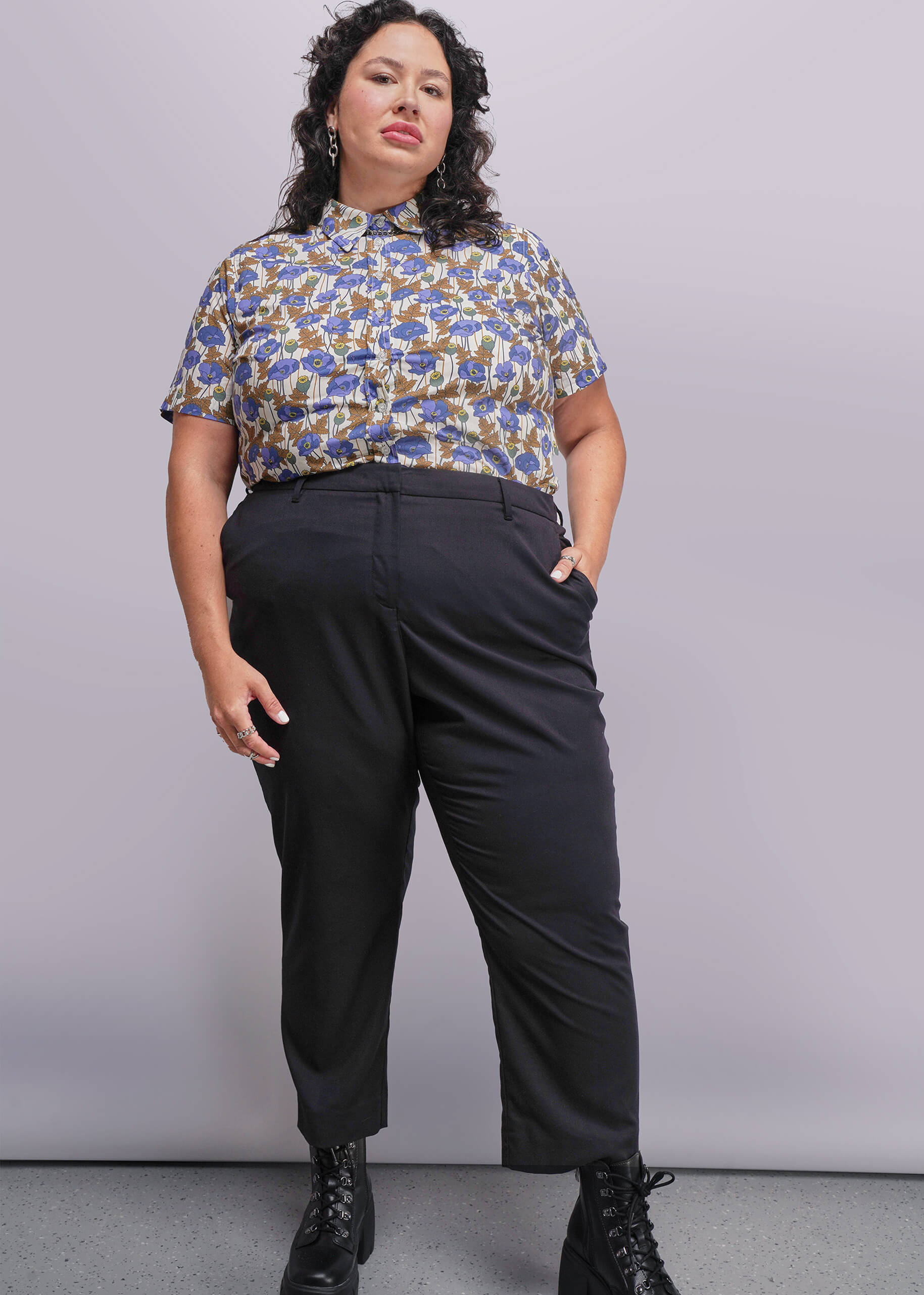 1X=Person wearing a patterned shirt and black pants against a plain background