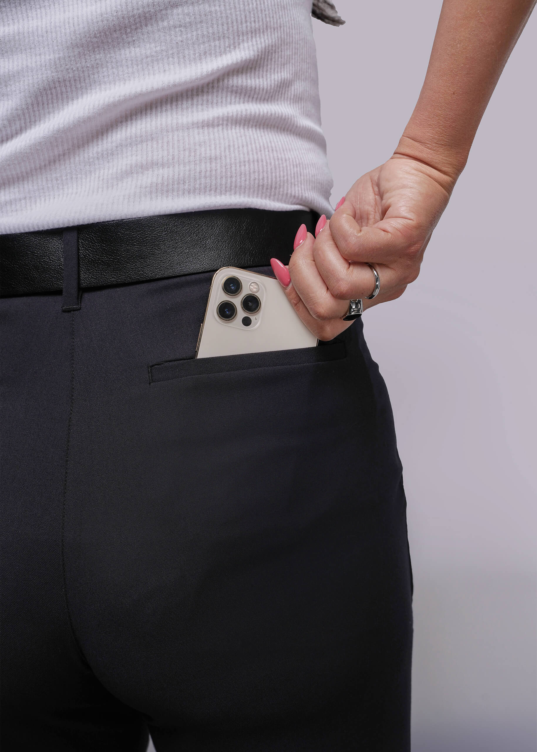 S=Person wearing black pants with a phone in the pocket against a plain background