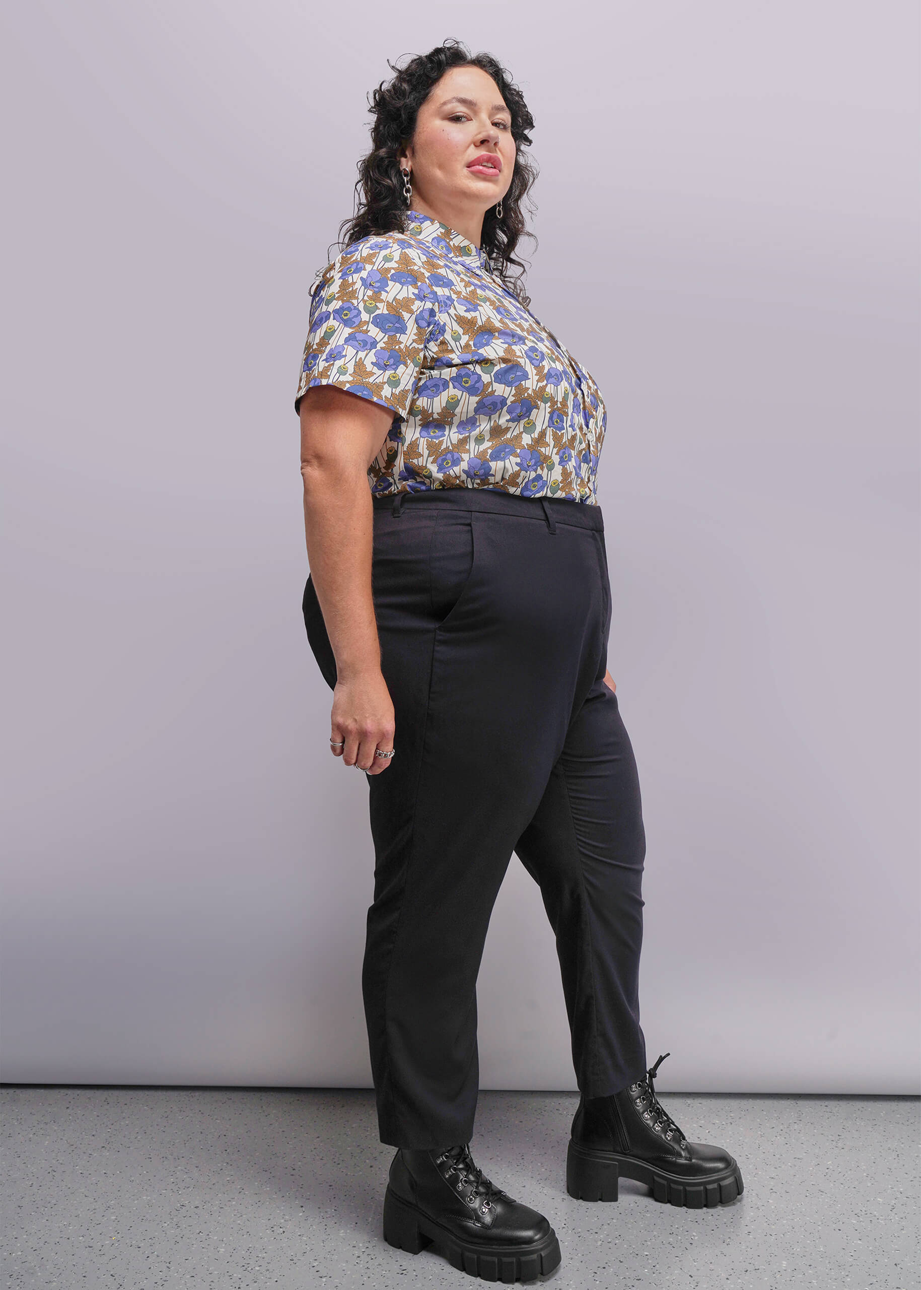 1x=Person wearing a patterned shirt and black pants against a plain background