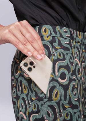 S=Person wearing patterned pants with a phone in a pocket against a light purple background