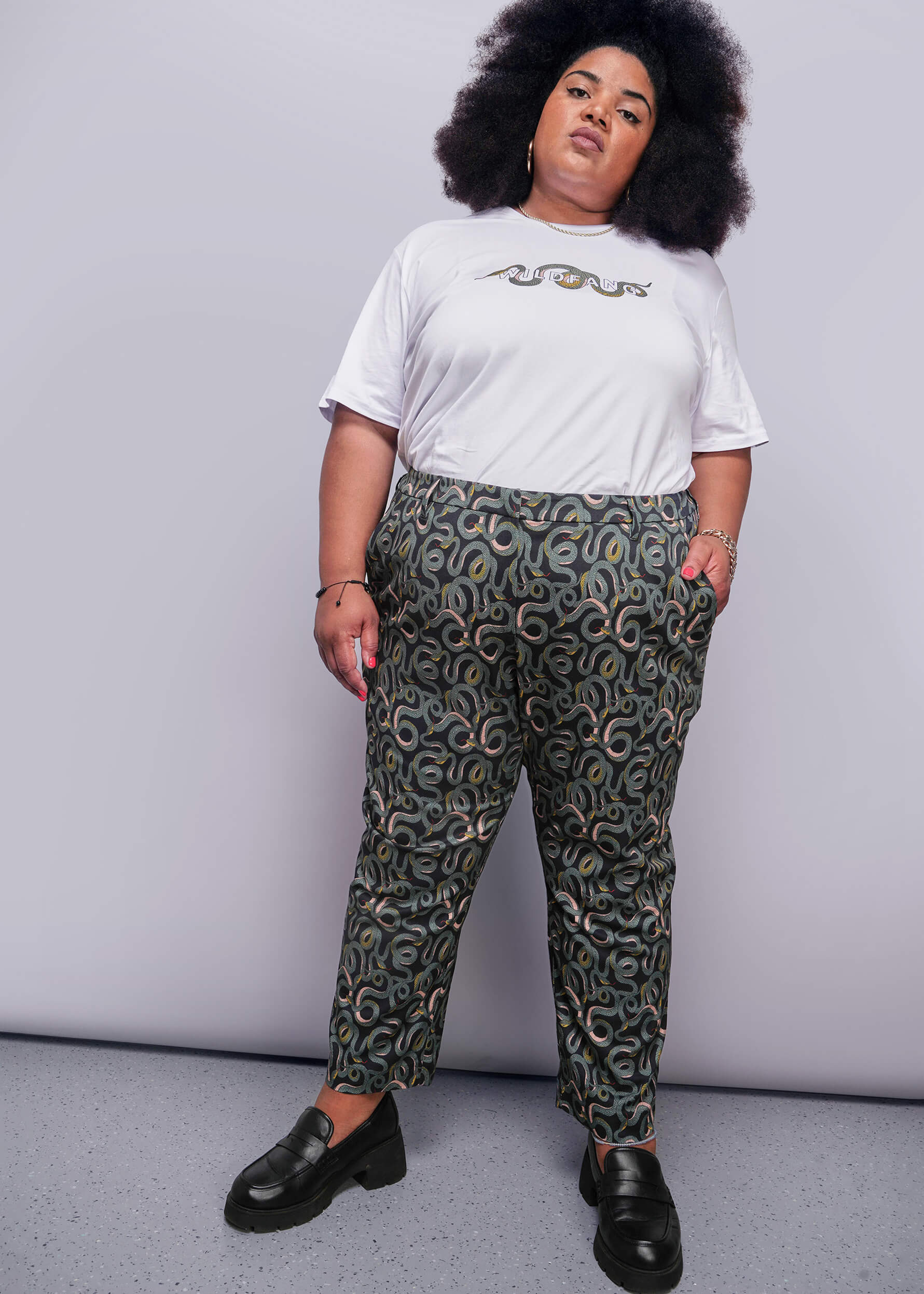 1X=Person wearing a white t-shirt and patterned pants against a plain background