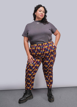 S=Woman wearing a gray t-shirt and colorful patterned pants against a plain background