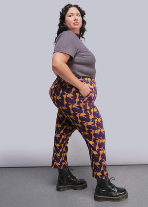 S=Person wearing a gray shirt and patterned pants against a plain background