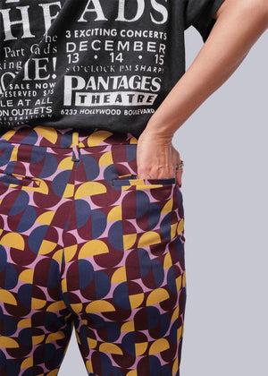 S=Person wearing a black t-shirt with white text and colorful patterned pants.