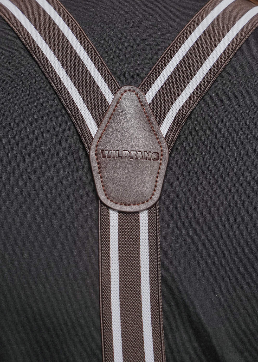 Close-up back view of a person wearing brown suspenders with white stripes over a dark gray shirt, showing the central leather connector and strap details.