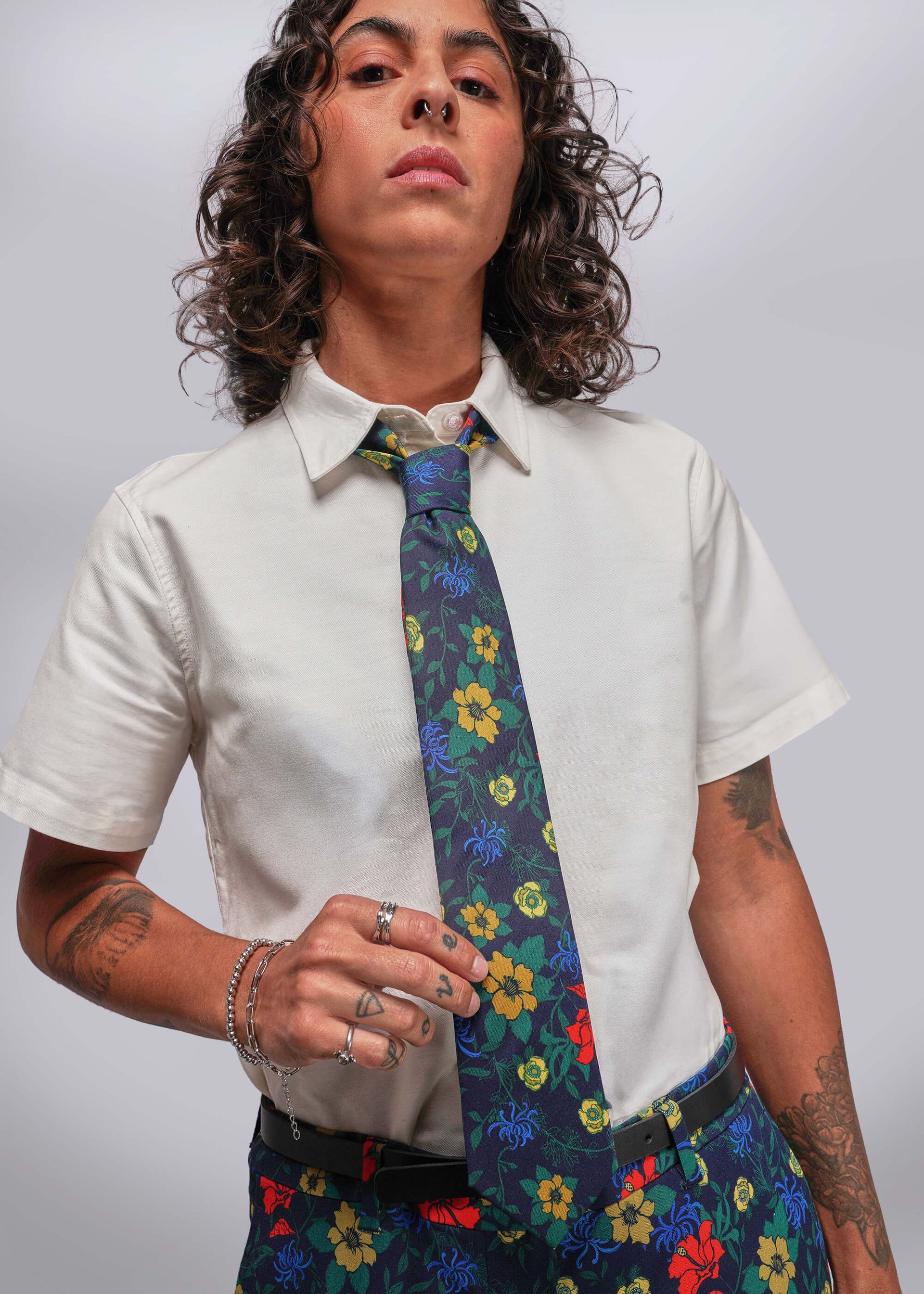 Person wearing a white shirt and colorful floral tie against a plain background