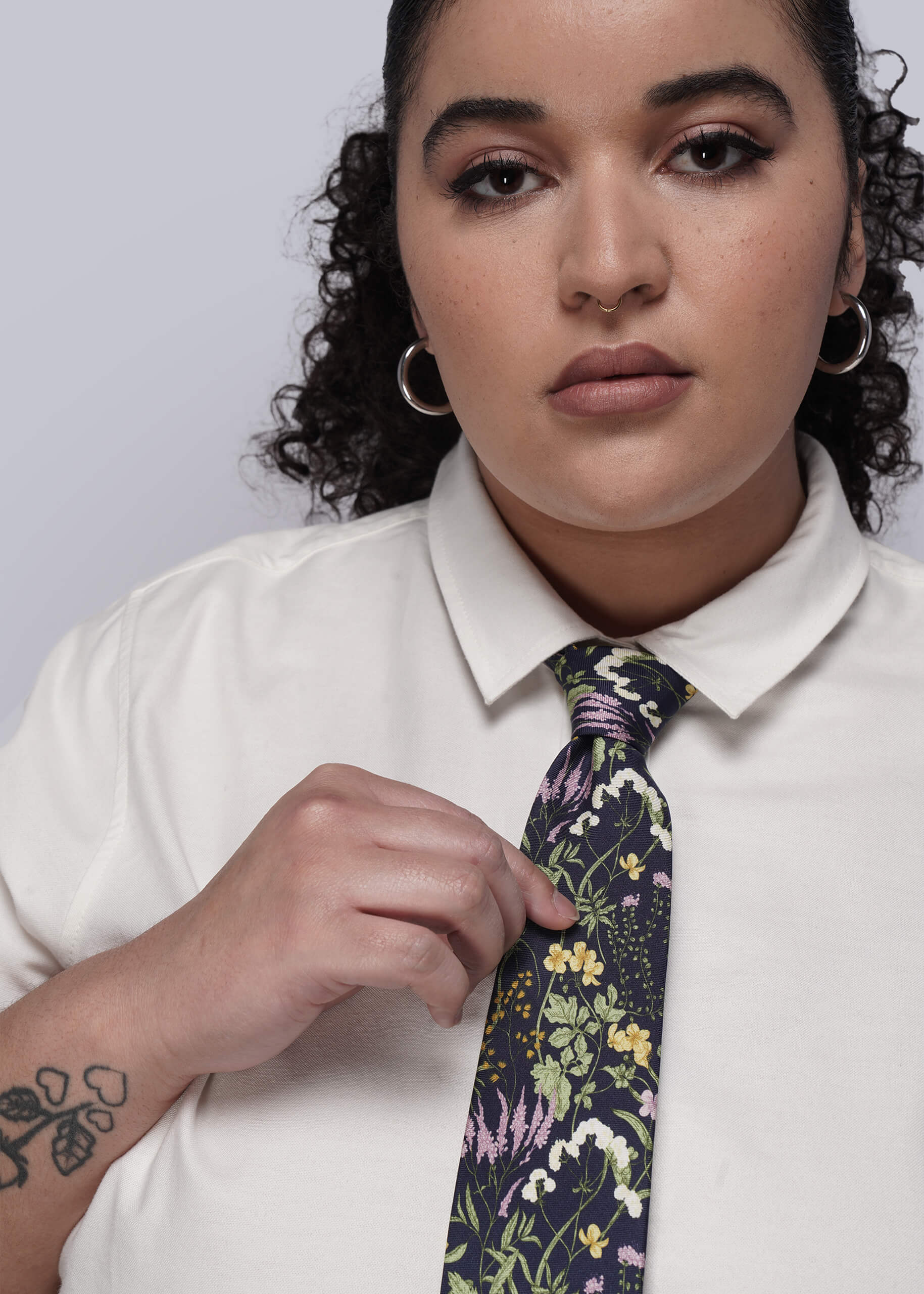 Person wearing a white shirt and floral tie against a plain background