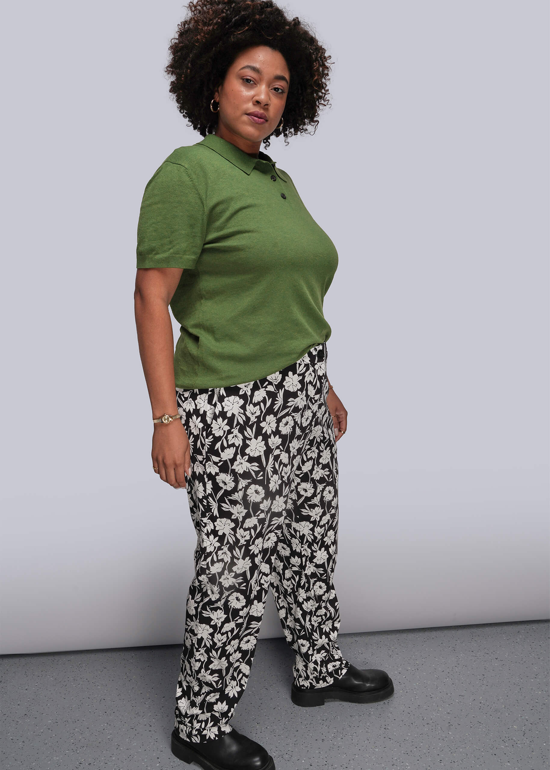 1X=Person wearing a green polo shirt and patterned pants against a plain background