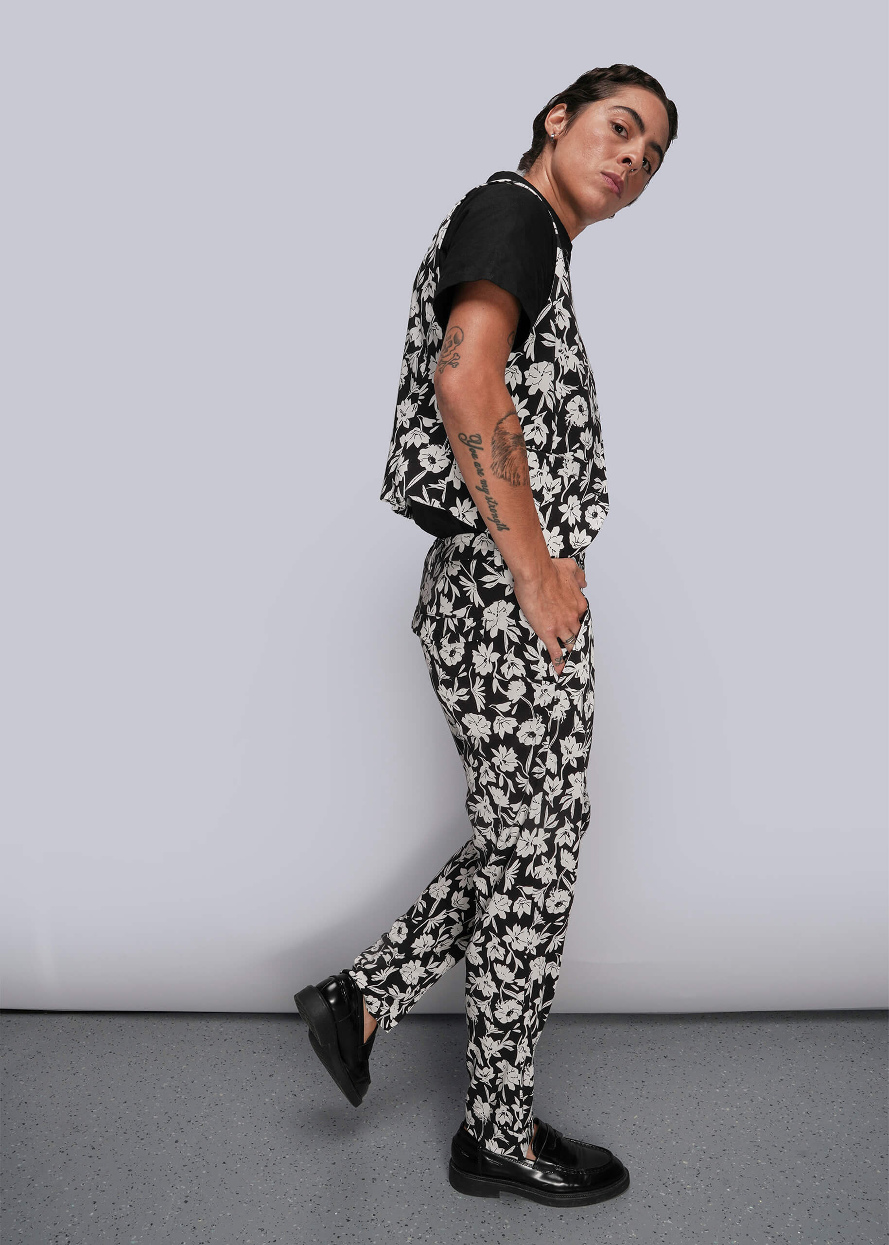 S=Person wearing a black and white floral outfit against a plain background