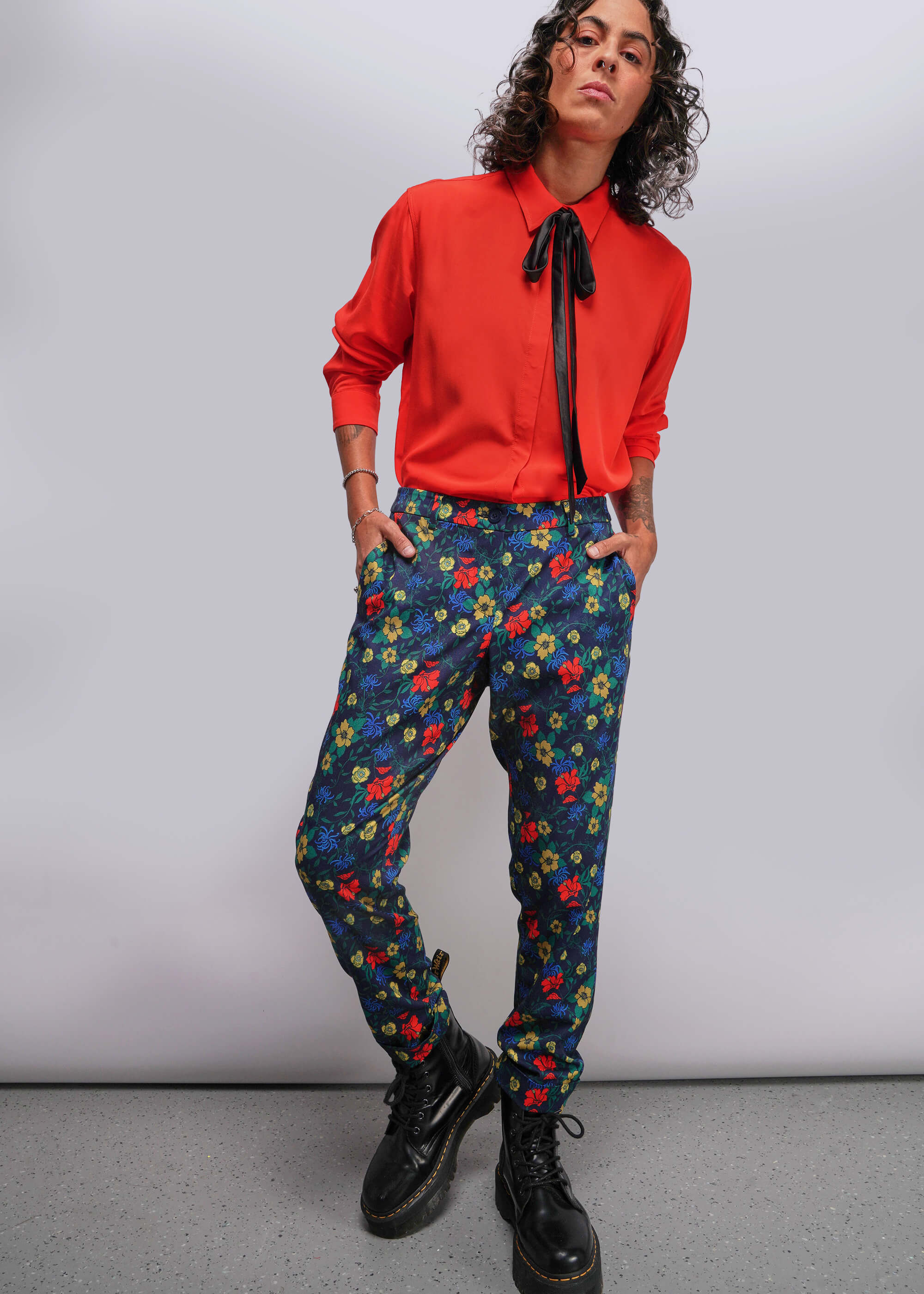 Person wearing a red shirt and colorful floral pants against a plain background