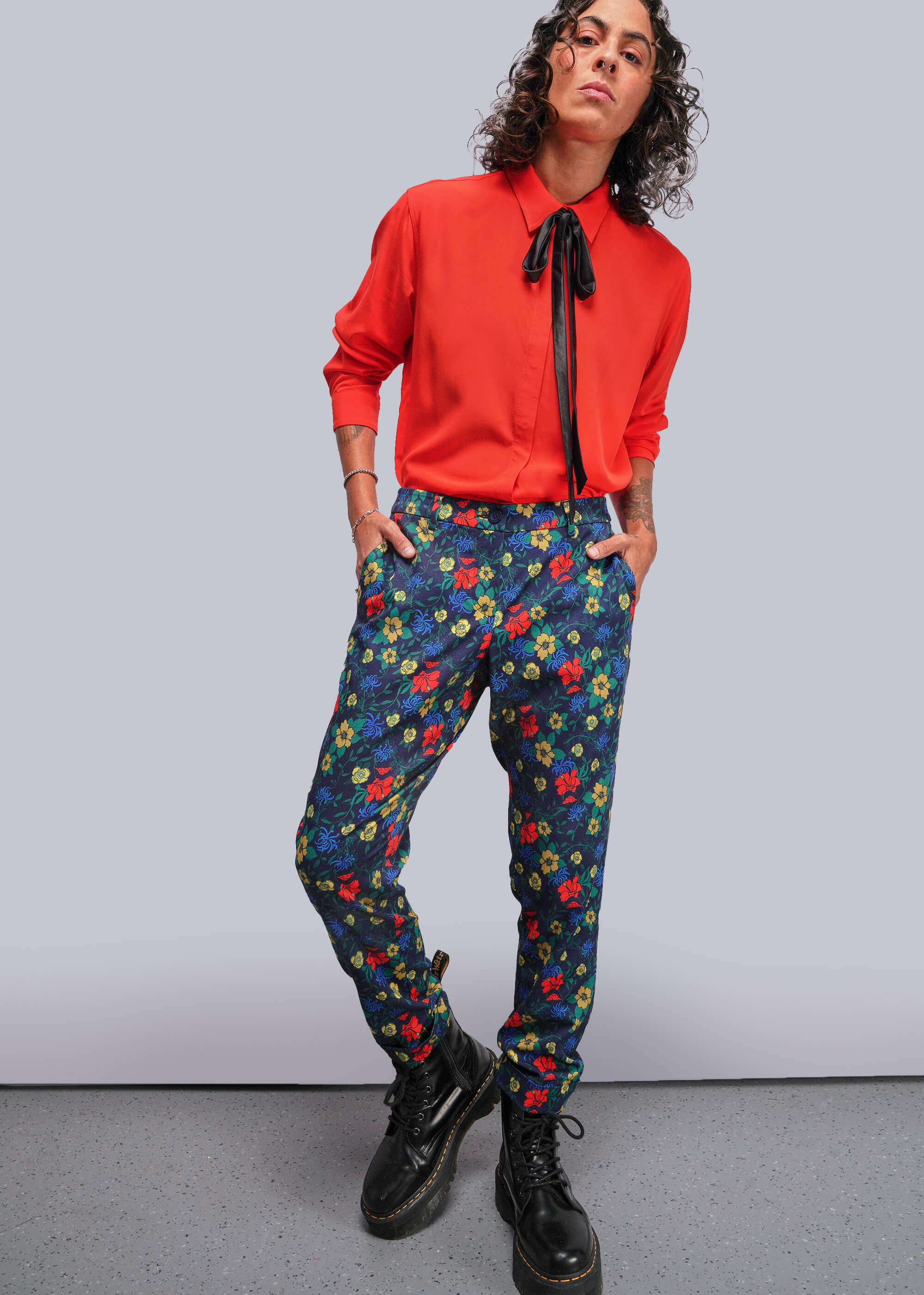 Person wearing a red shirt and colorful floral pants against a plain background