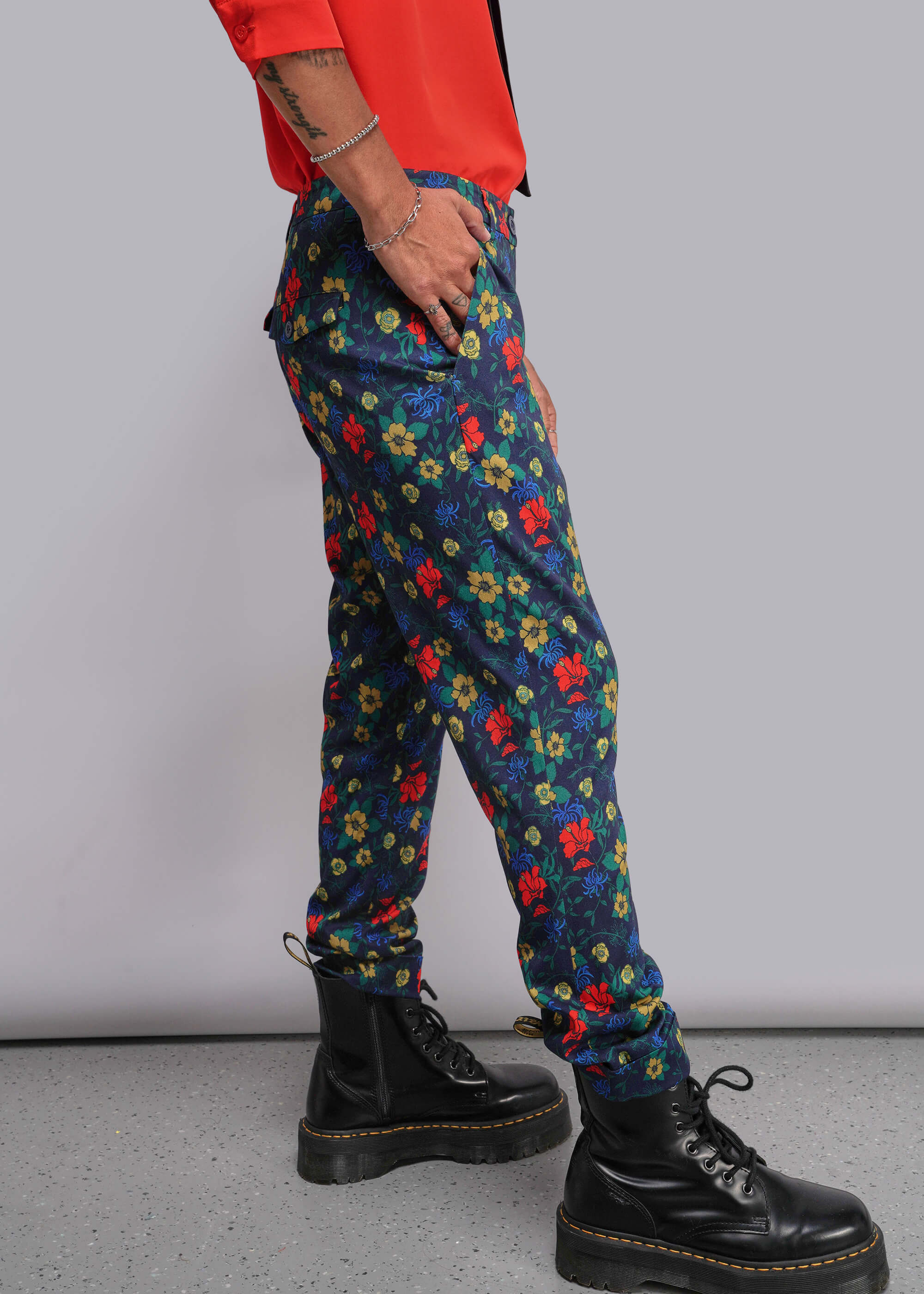 Person wearing colorful floral pants and black boots on a plain background