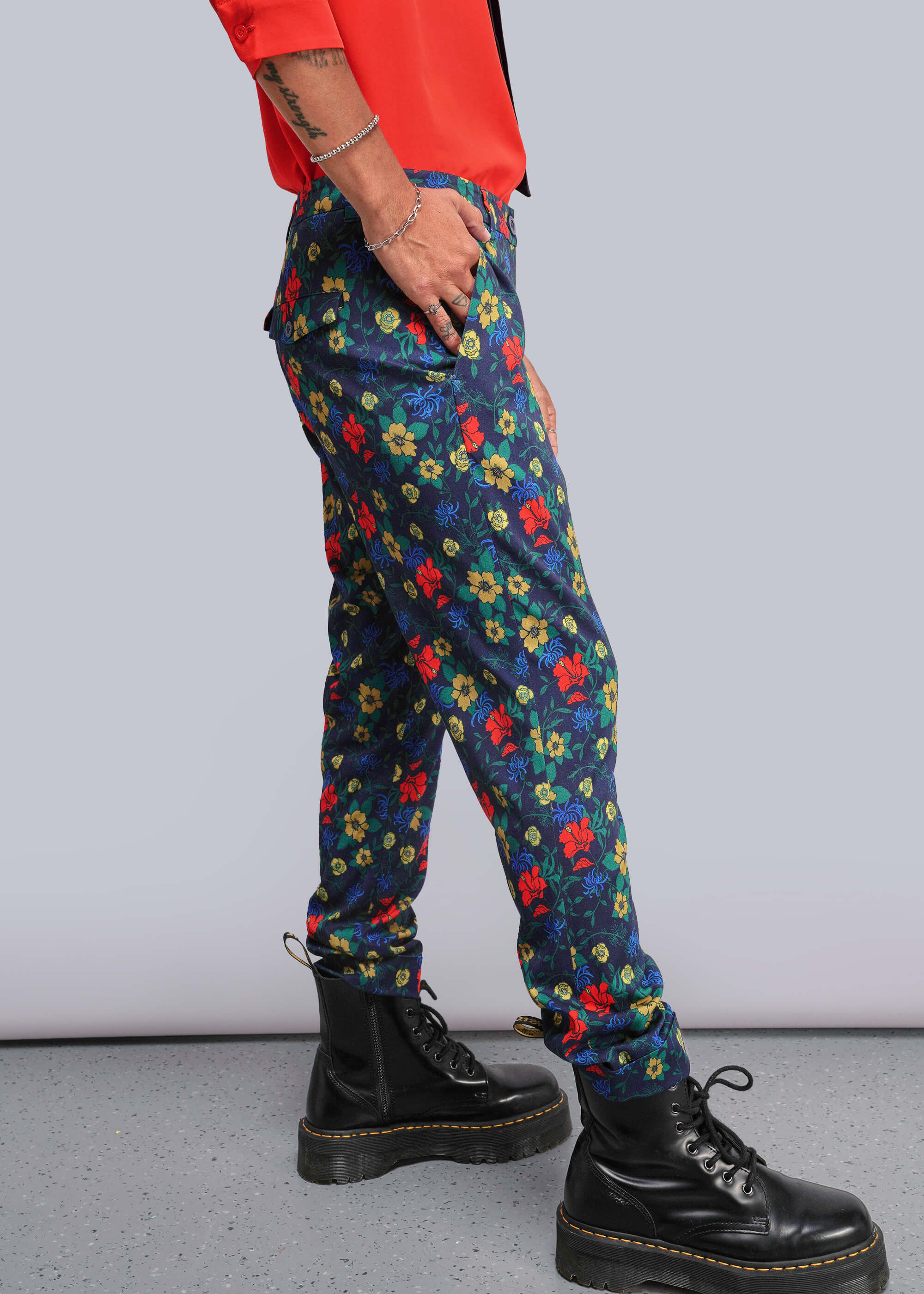 Person wearing colorful floral pants and black boots on a plain background