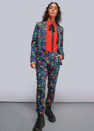 S=Person wearing a colorful floral suit with a red shirt and black boots on a plain background