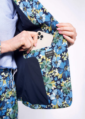 S=Close up of hand placing iphone in interior blazer pocket showing navy blue lining of floral printed blazer.