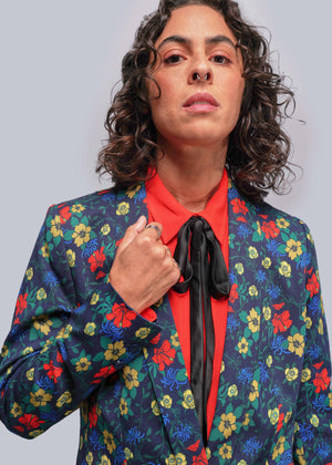 S=Person wearing a colorful floral blazer over a red shirt with a plain background