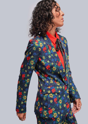 S=Person wearing a colorful floral suit with a red shirt on a gray background
