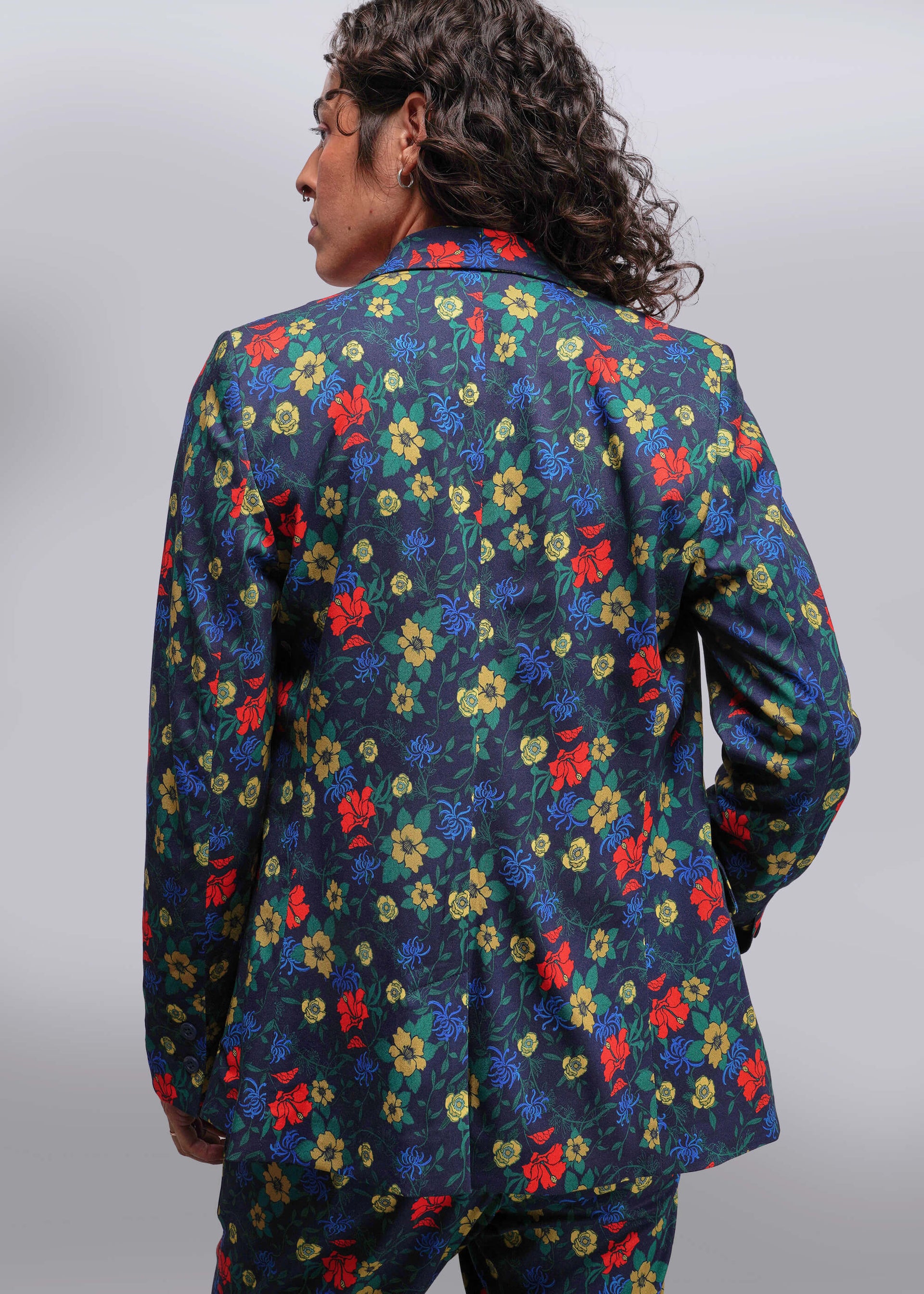 S=Person wearing a colorful floral patterned jacket on a plain background
