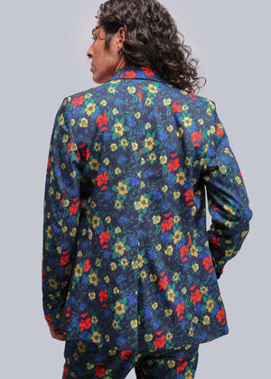 S=Person wearing a colorful floral patterned jacket on a plain background
