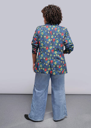 1X=Person wearing a colorful floral jacket and blue jeans against a plain background