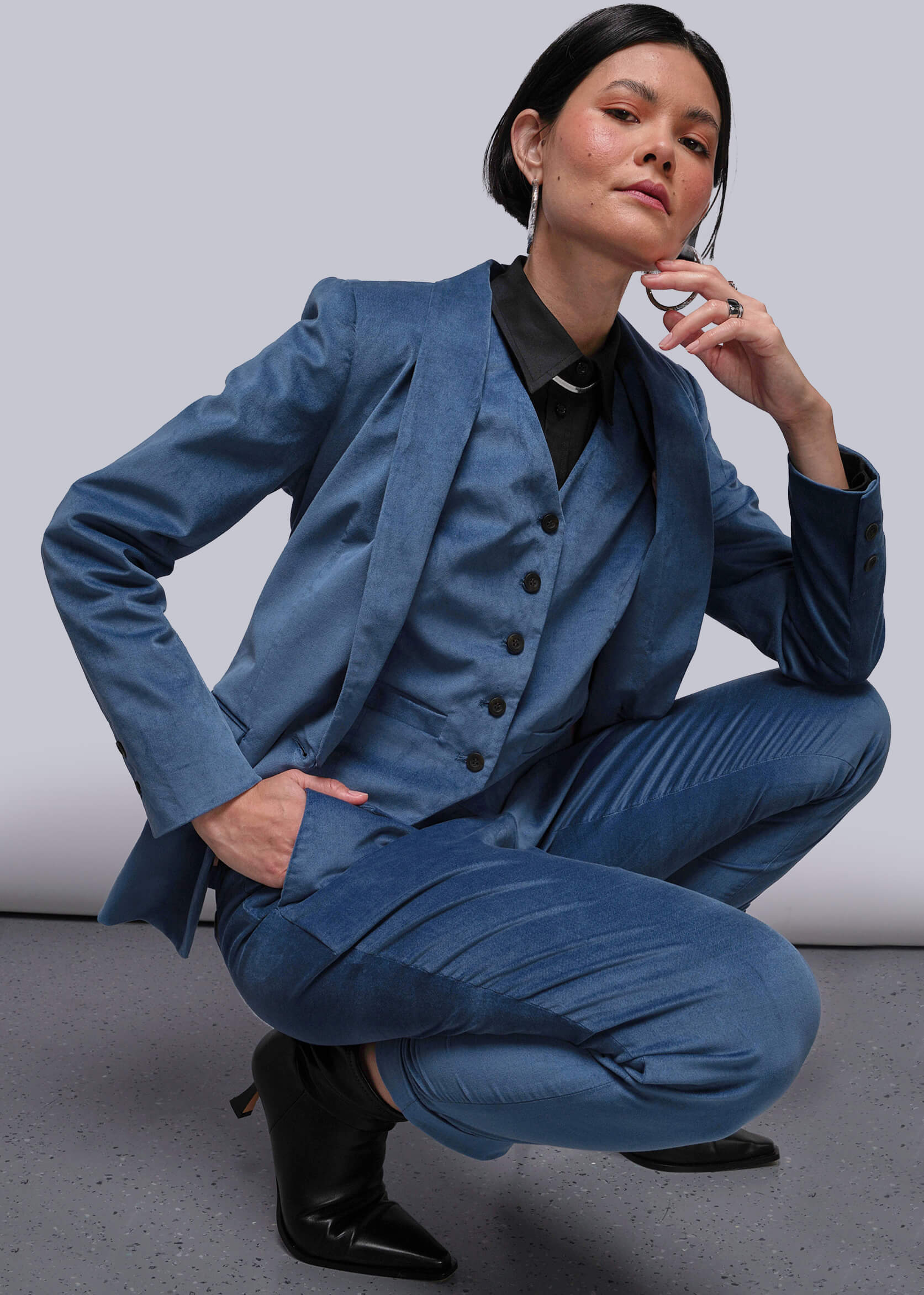 Person wearing a blue suit sitting on the floor against a plain background