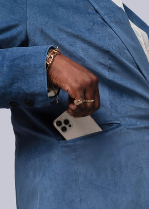 1X=Person wearing a blue suit with a phone in the pocket against a white background