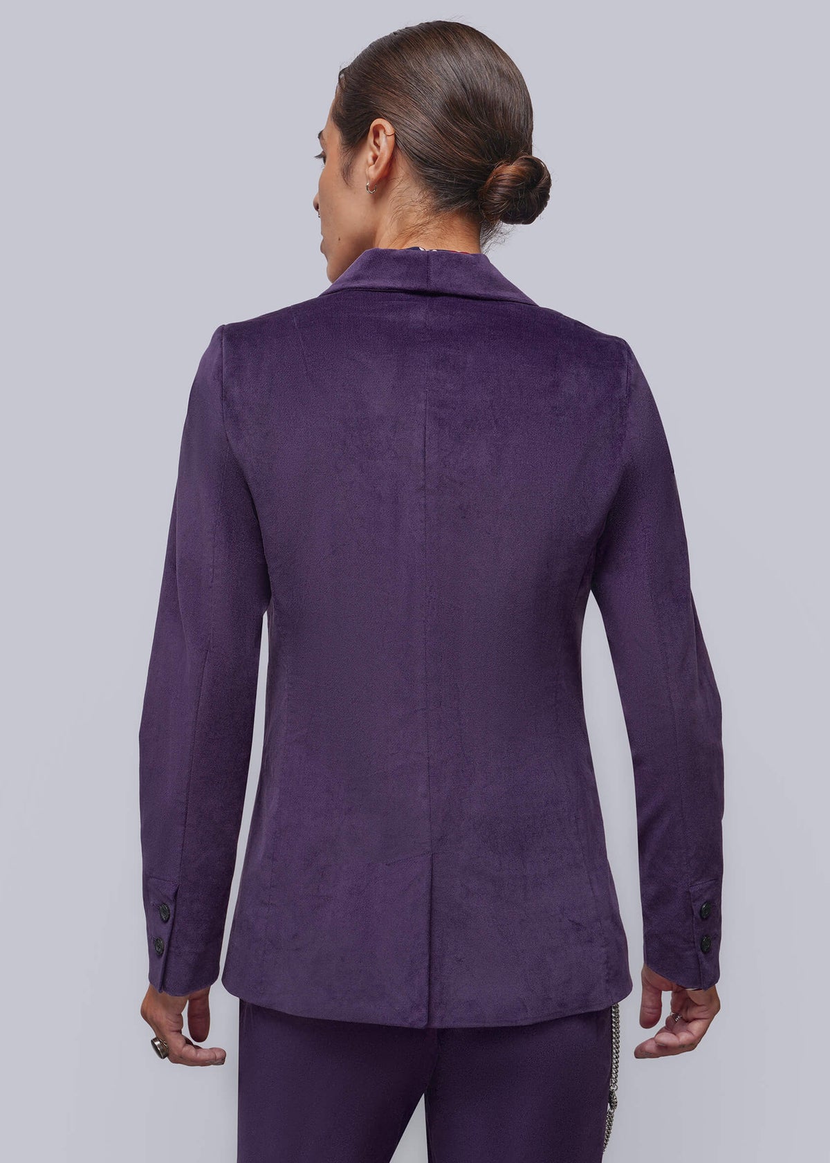 S=A person shown from the back wearing a tailored purple blazer with matching trousers against a light gray studio background.