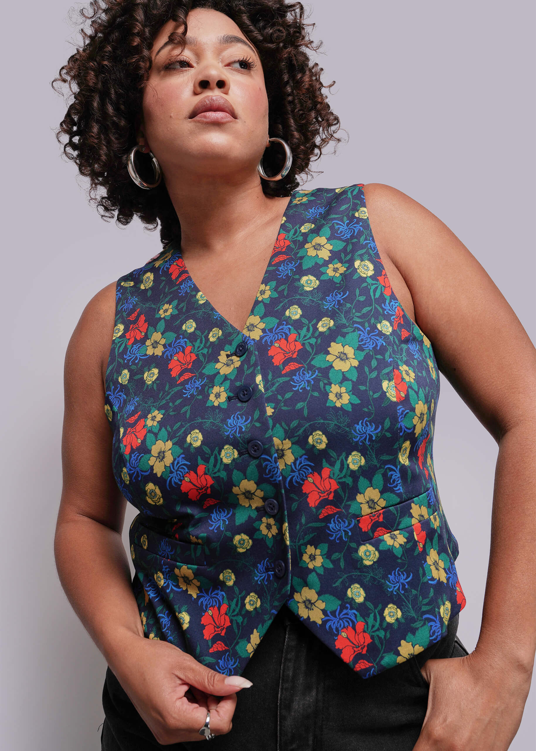 1X=Woman wearing a colorful floral vest against a plain background