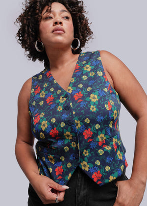 1X=Woman wearing a colorful floral vest against a plain background