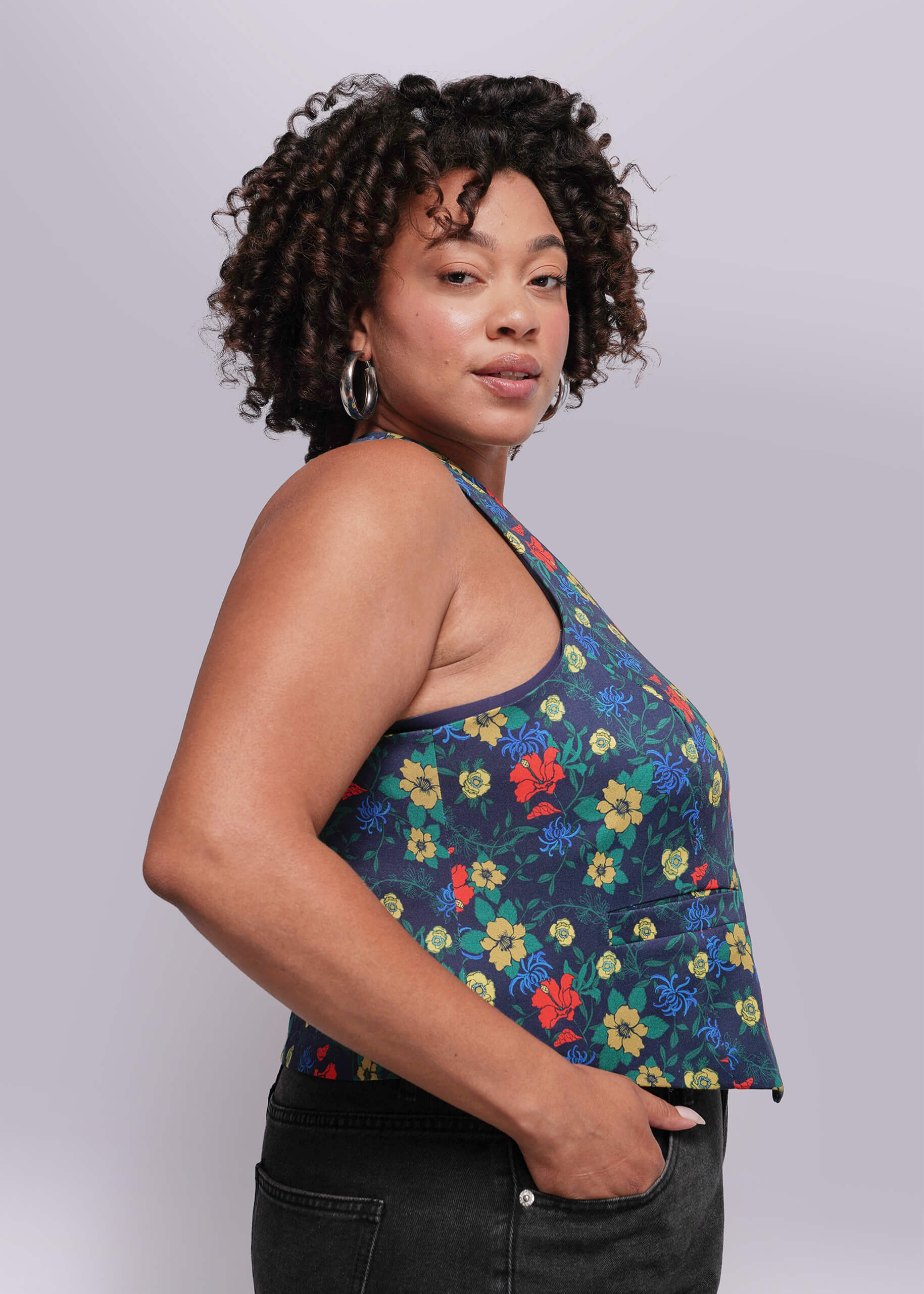 1X=Woman wearing a colorful floral top against a plain background