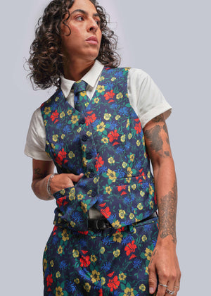 S=Person wearing a colorful floral vest over a white shirt on a gray background