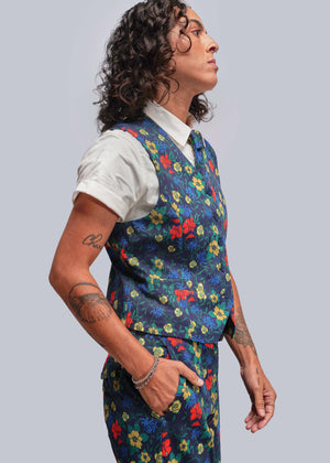 S=Person wearing a colorful floral vest over a white shirt on a plain background