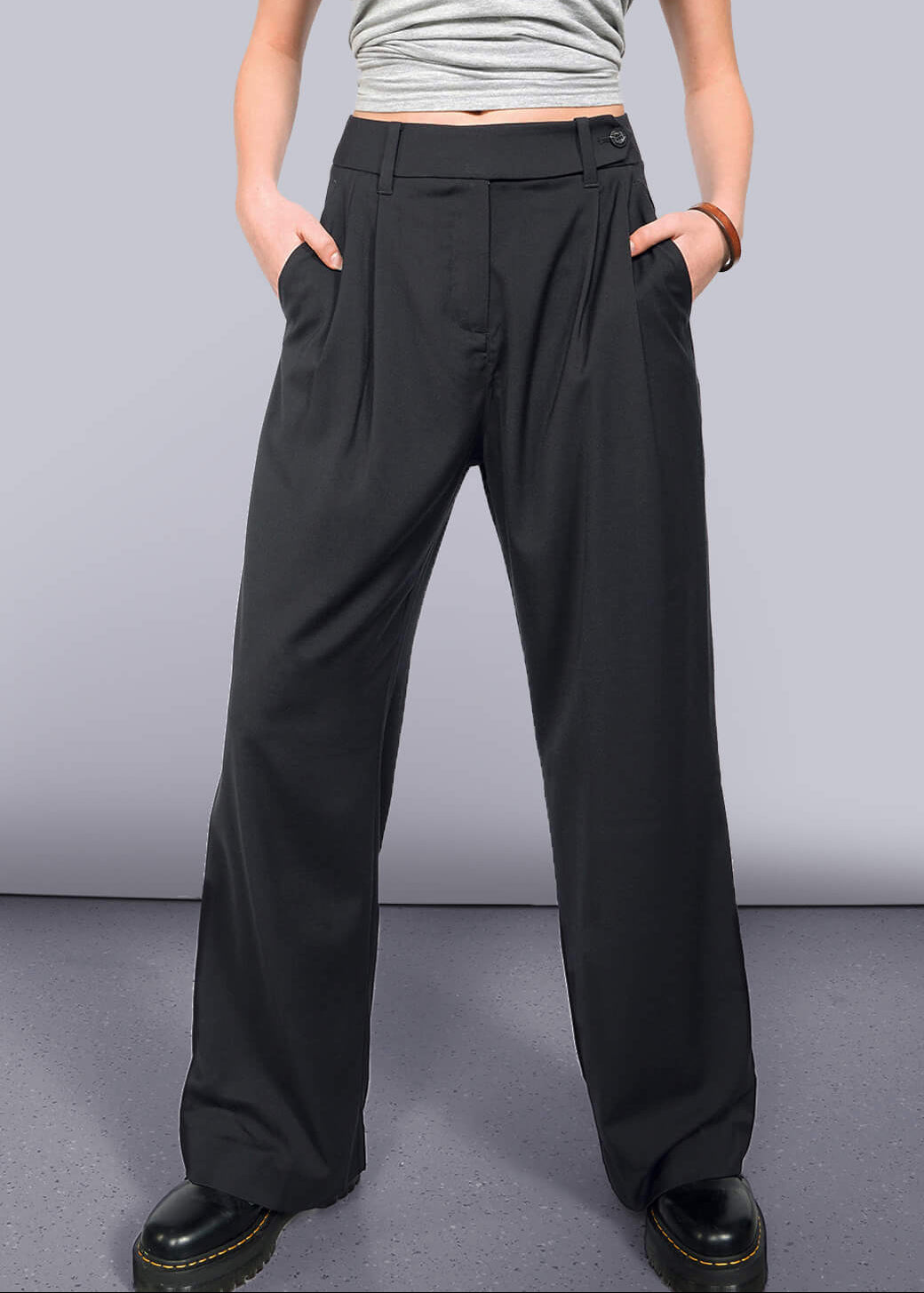 Wide leg black pant on model pictured from the waist down on grey background