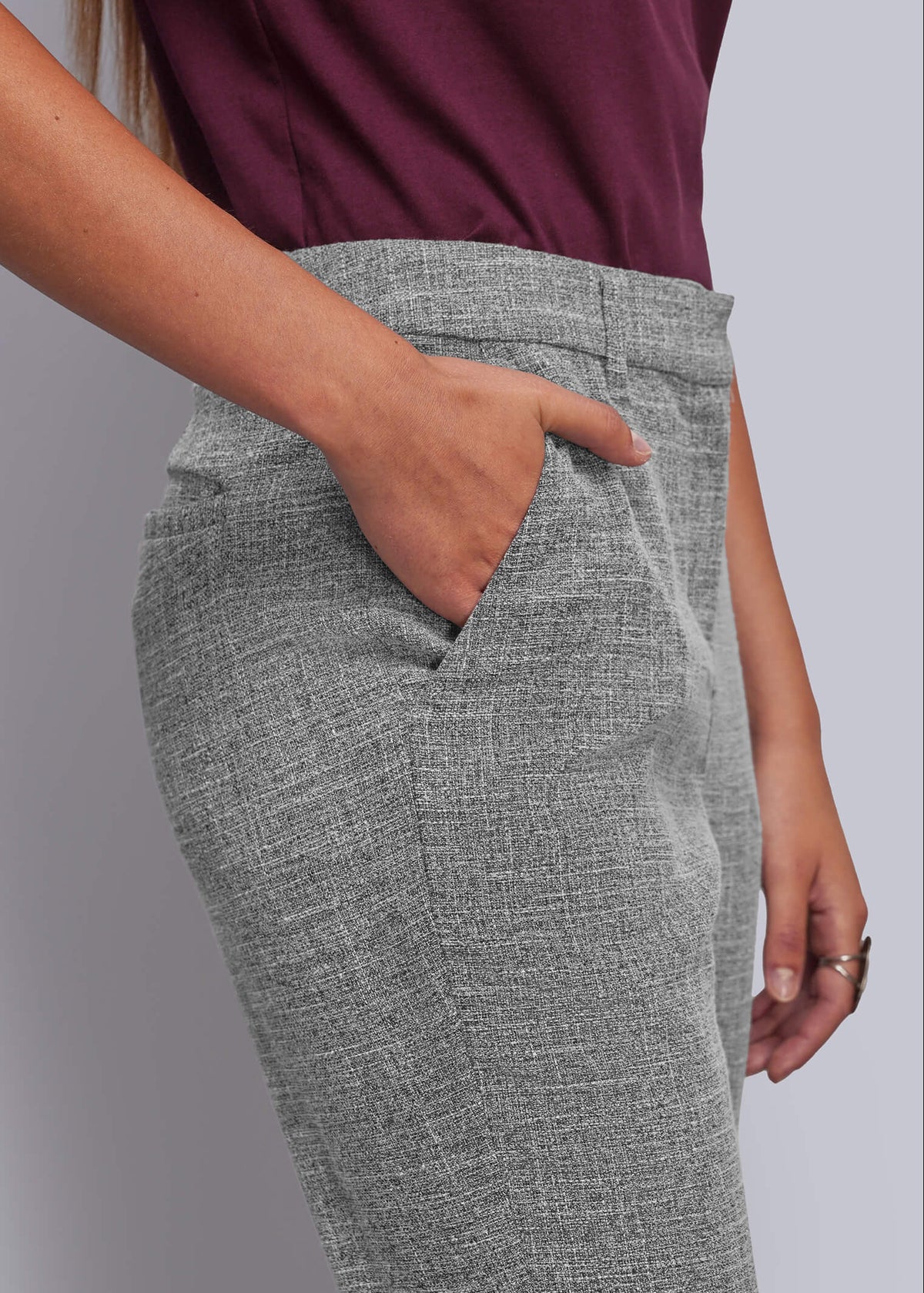 S=A close-up of a person wearing gray textured trousers with a side pocket, paired with a dark burgundy top, against a plain light gray background.