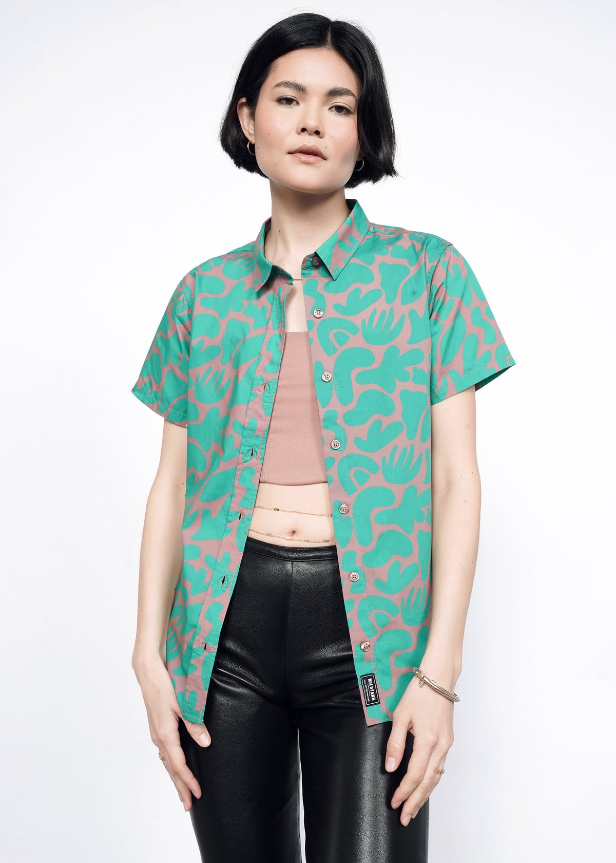 Model wearing the Essential Button Up in Abstract Emerald in size XS, with black faux leather leggings and the 6-Way Corset in Rose Brown