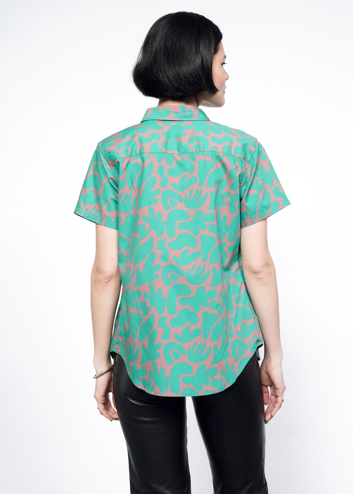 Back image of model wearing the Essential Button Up in Abstract Emerald in size XS, with black faux leather leggings