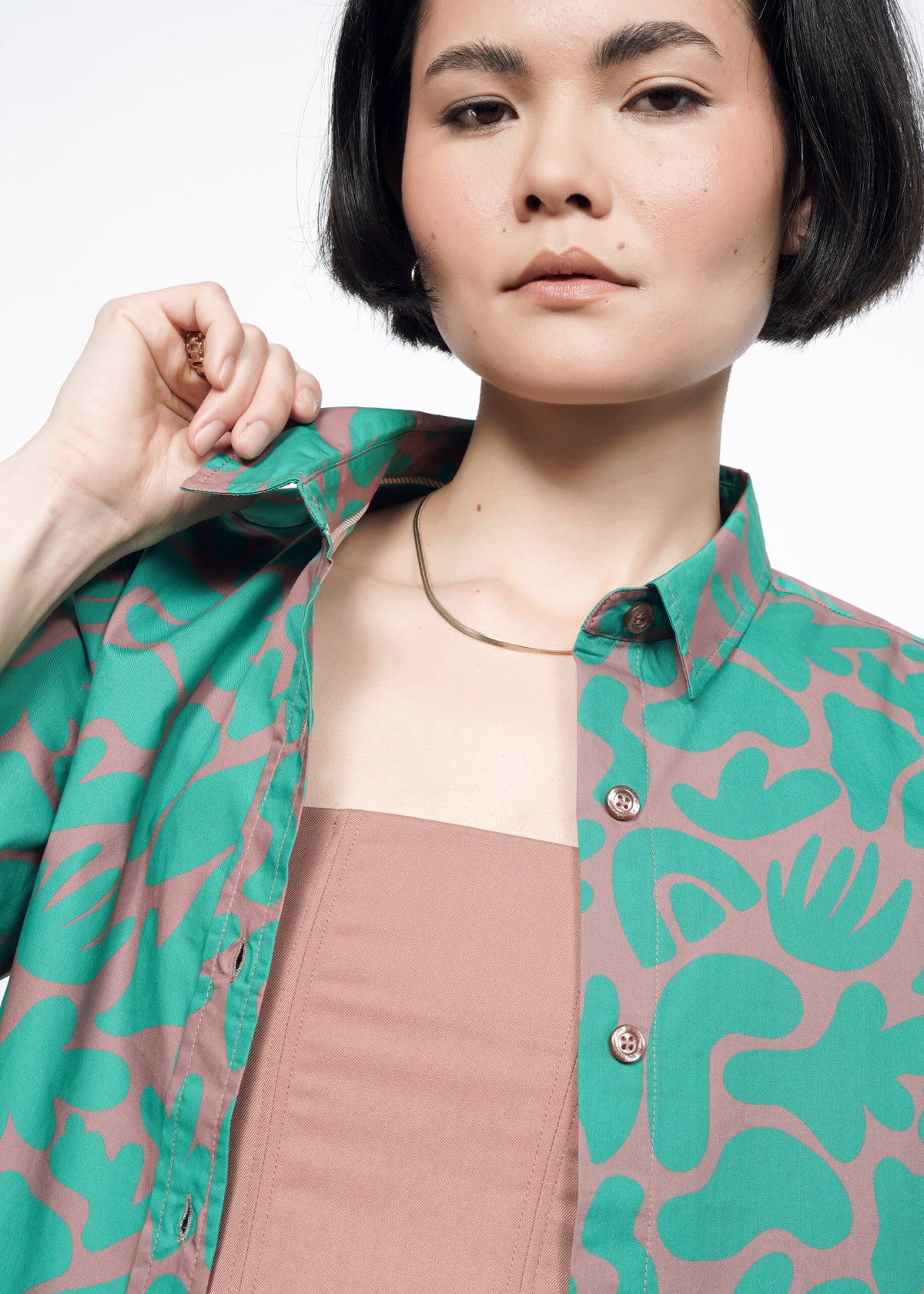 Close-up of model wearing the Essential Button Up in Abstract Emerald, also wearing 6-Way Corset in Rose Brown
