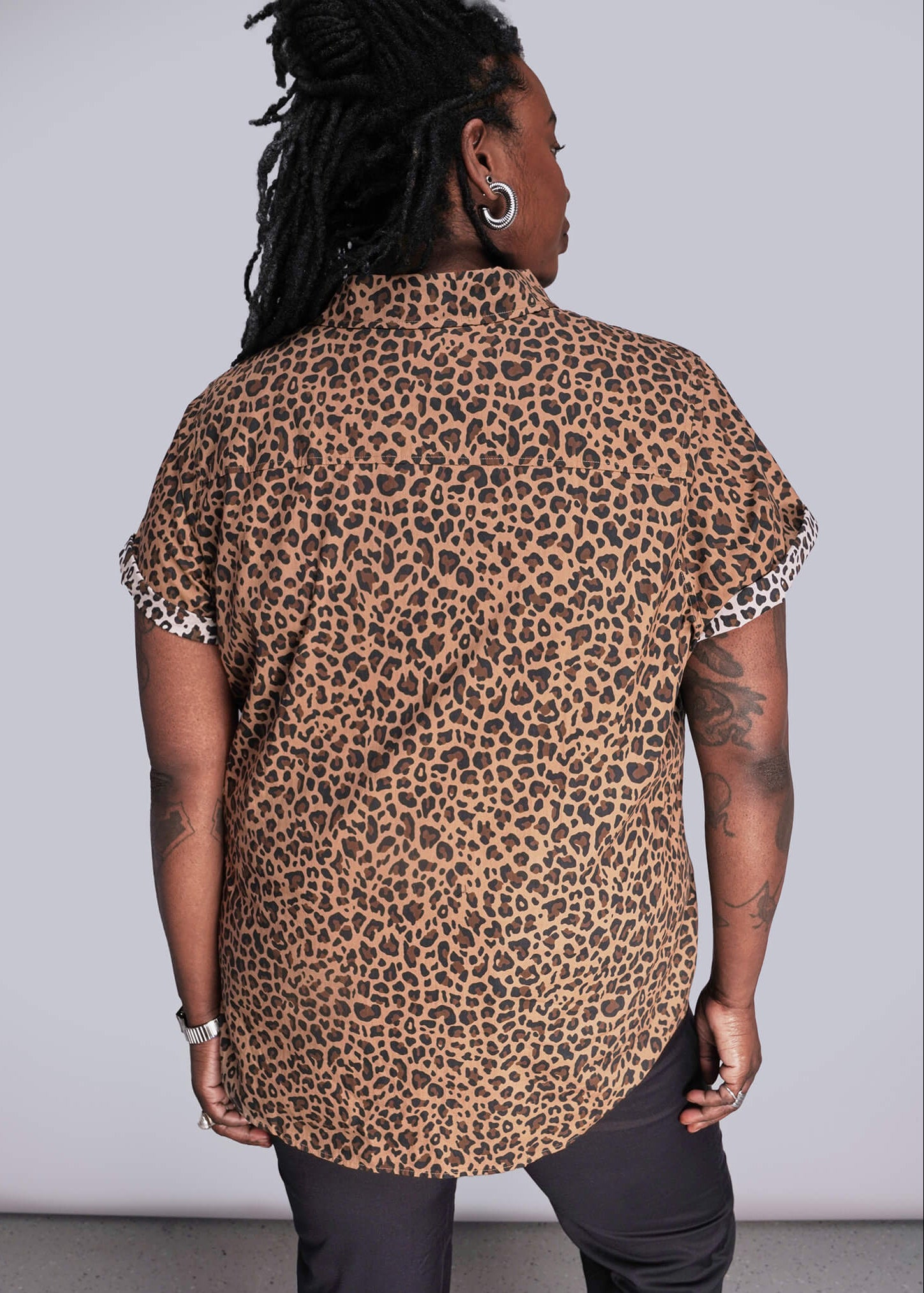 1X=Person wearing a leopard print shirt with white trim on a plain background