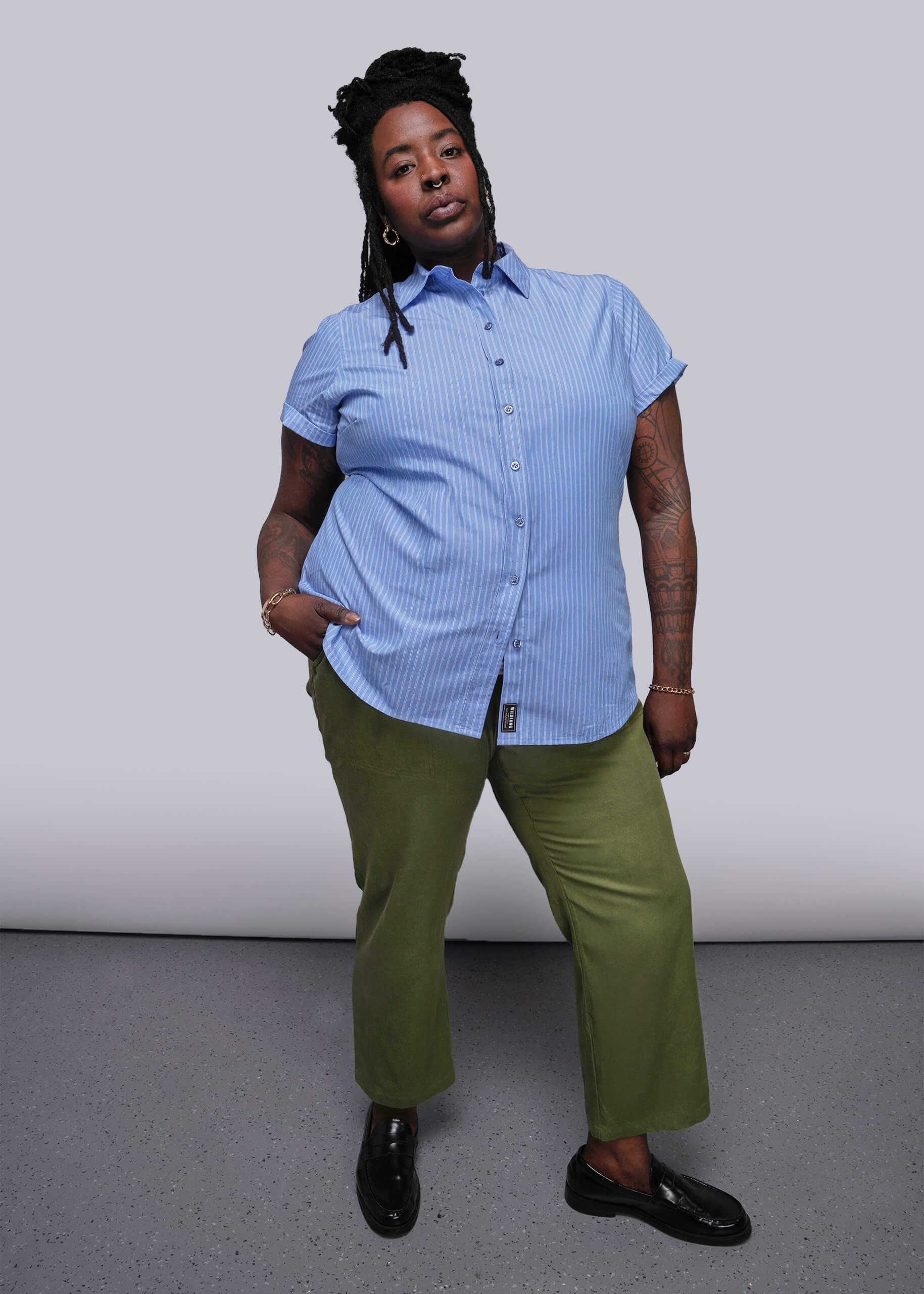 1X=Person wearing a blue striped shirt and green pants against a plain background