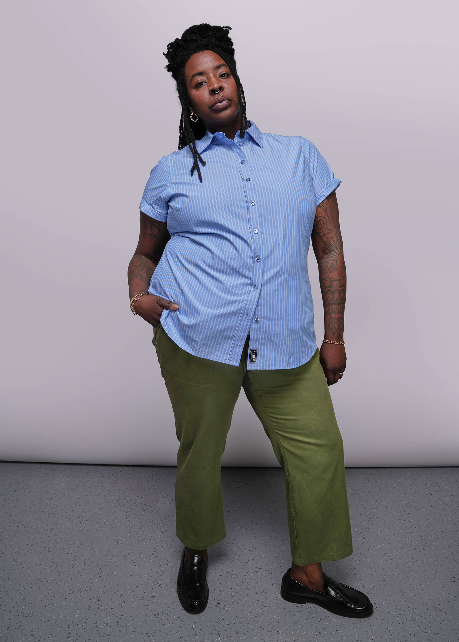 1X=Person wearing a blue striped shirt and green pants against a plain background