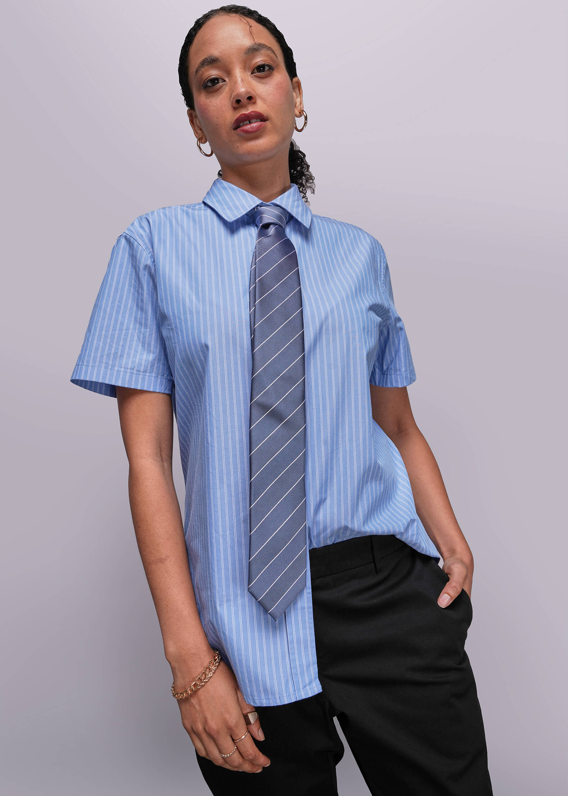 S=Person wearing a blue striped shirt with a tie against a plain background