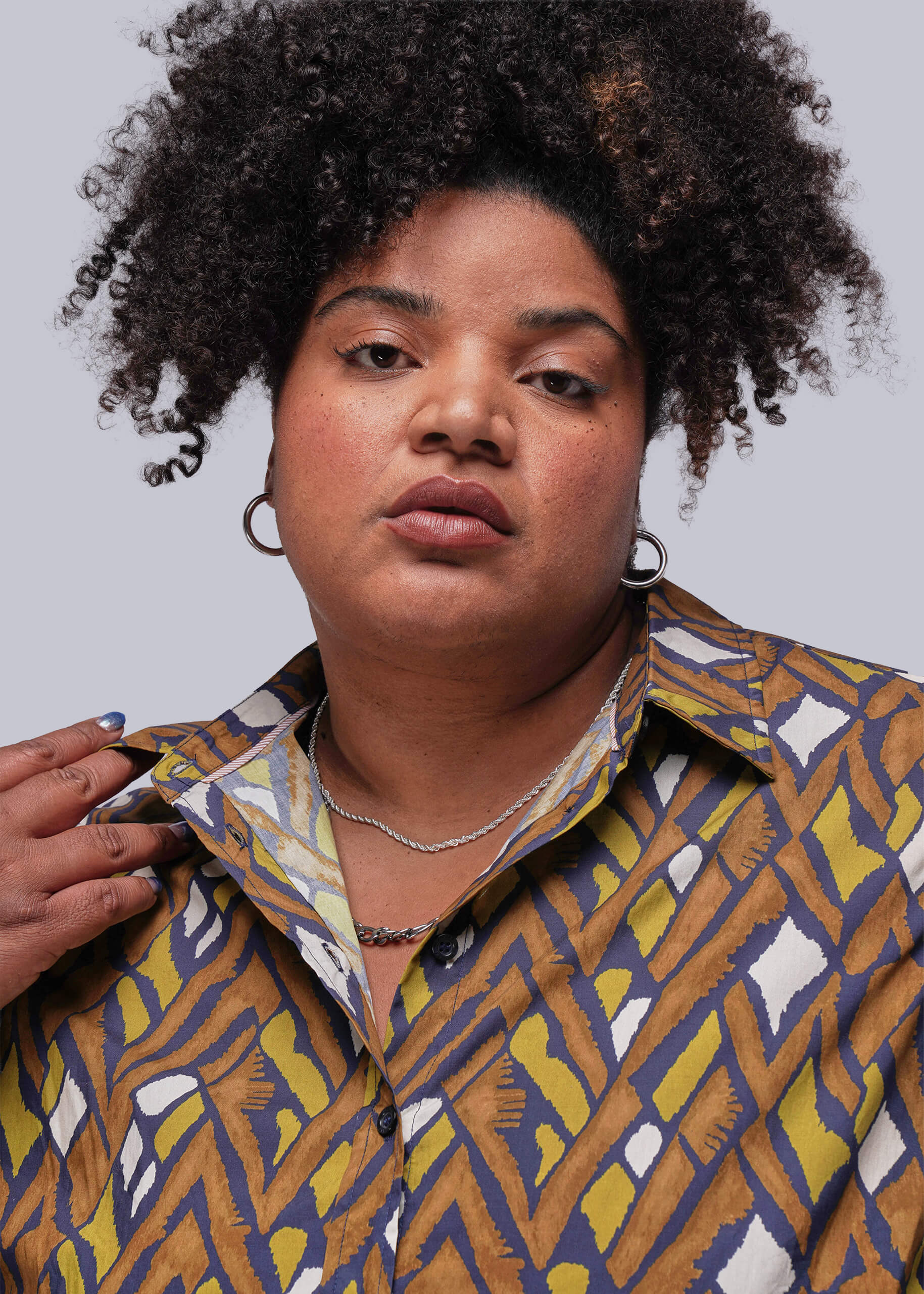 1X=Person wearing a patterned shirt with a plain background