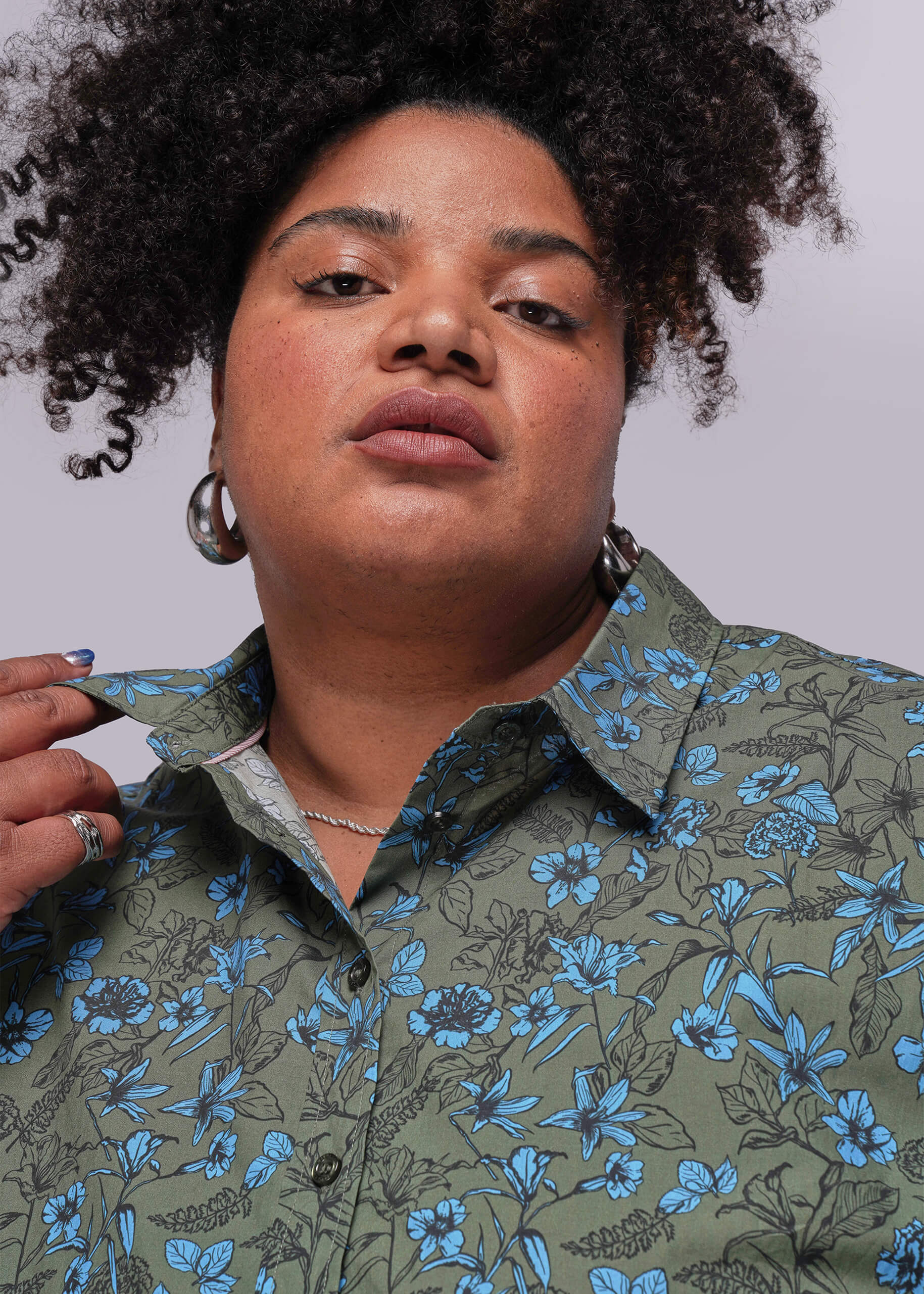 1X=Person wearing a green floral shirt against a plain background
