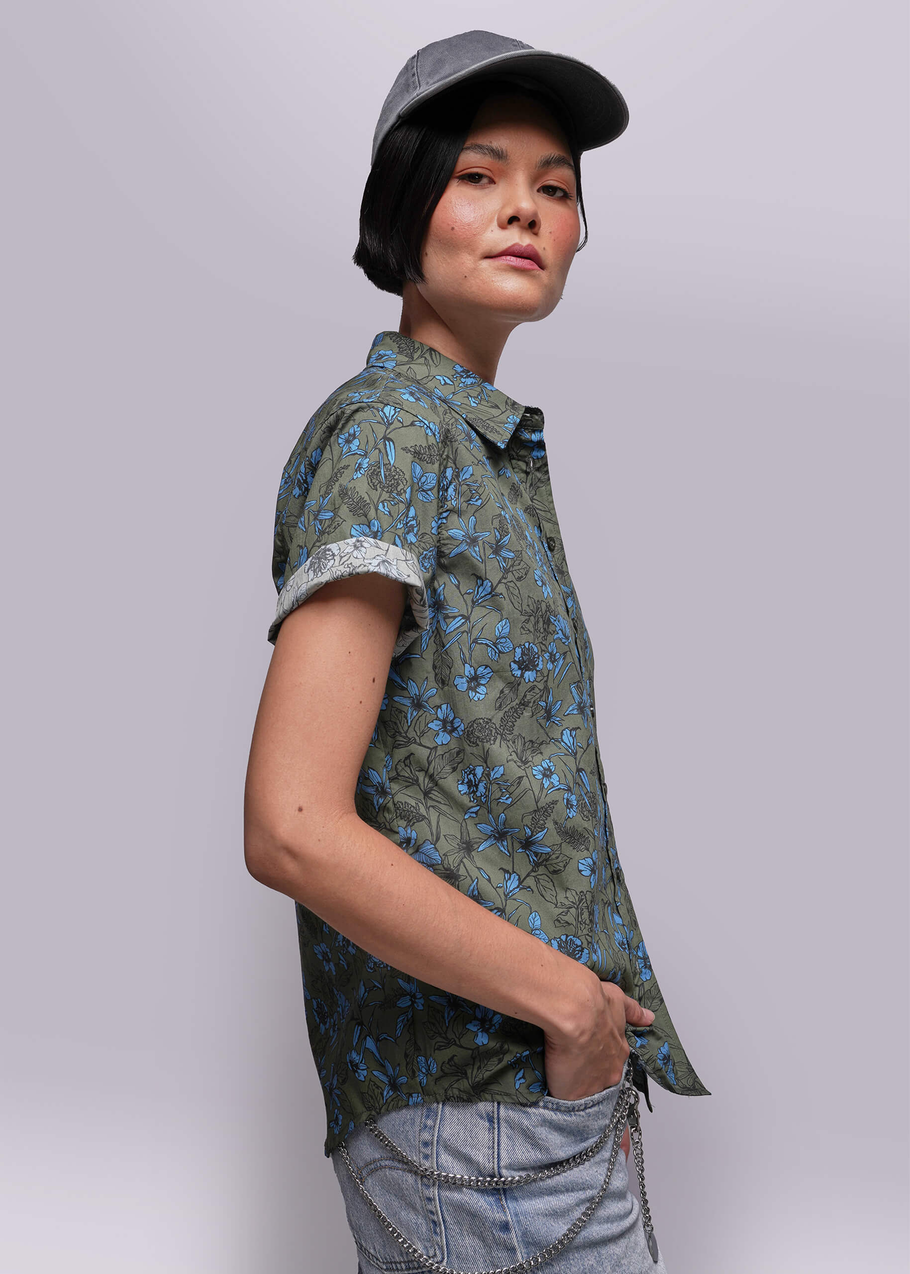 S=Person wearing a green floral shirt and gray cap against a light gray background