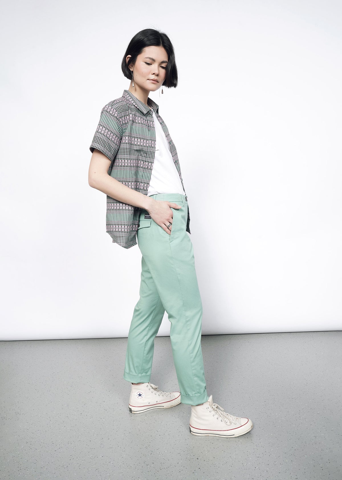 Side image of model wearing the Essential Button Up in Gingham Sage in size S, with a white T and sage Trousers