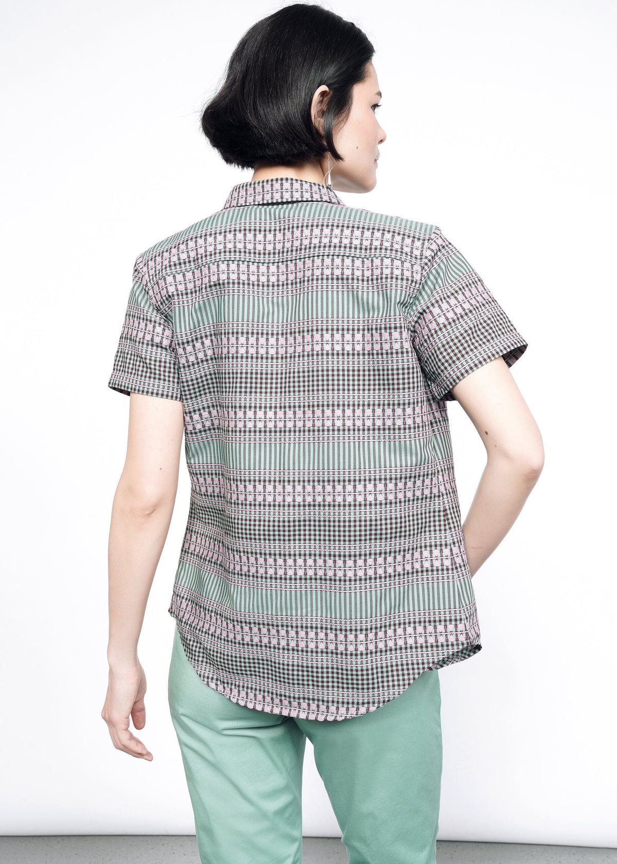 Back image of model wearing the Essential Button Up in Gingham Sage in size S, with sage Trousers