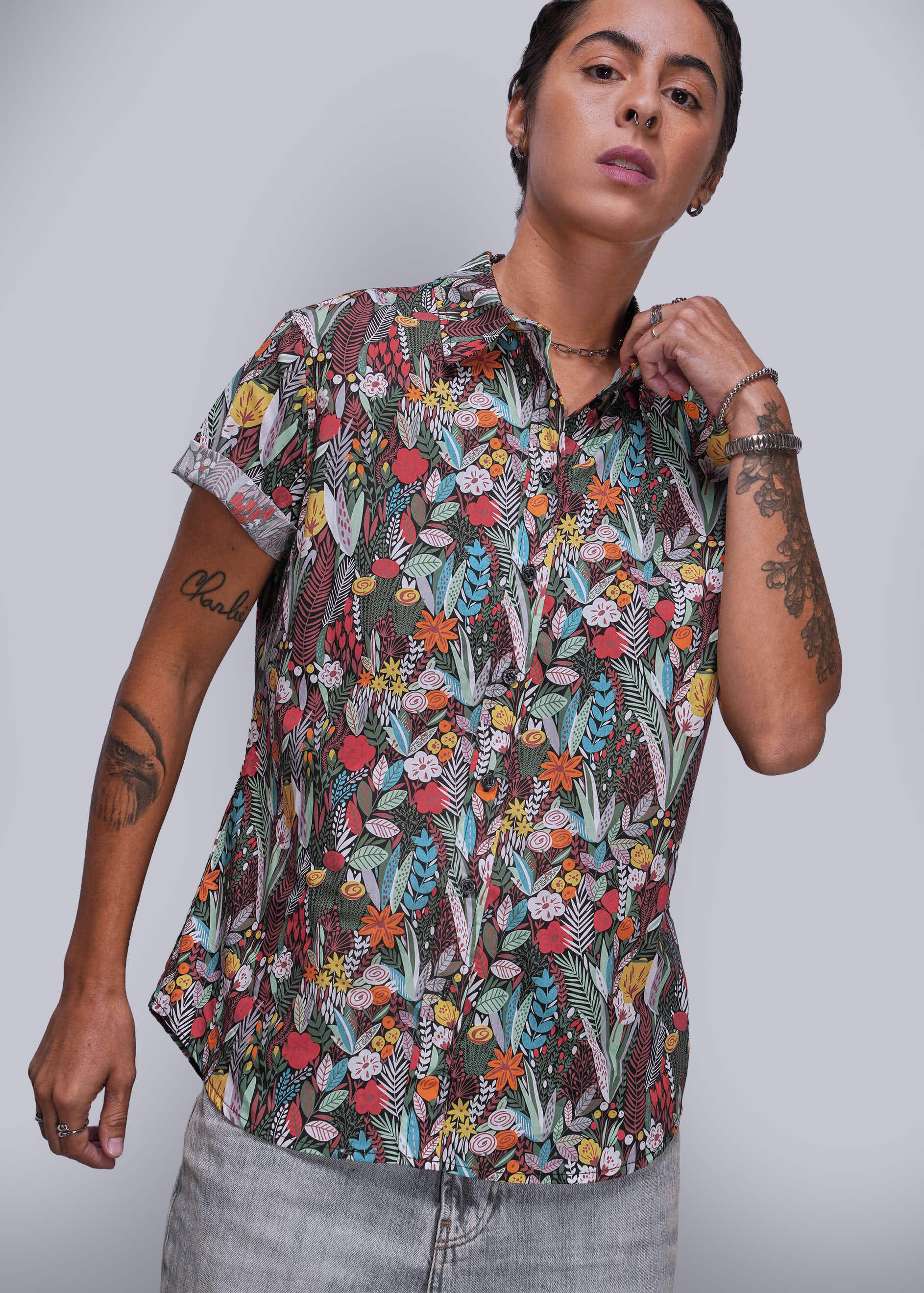 Person wearing a colorful floral patterned shirt against a plain background